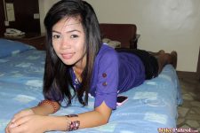 Cute Filipina in purple lays prone on bed