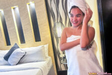 Joyful Asian poses in motel with only towel on