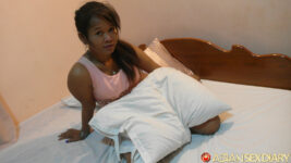 Asia Anal model sits on bed in motel
